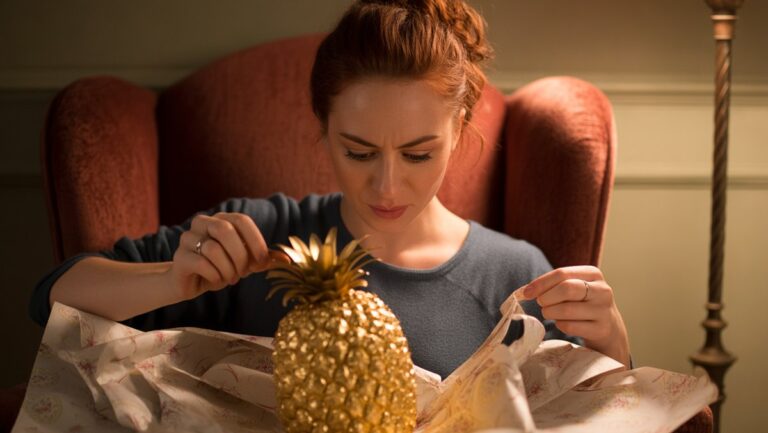 Realistiška žmogaus, turinčio nedidelį grimasą, nuotrauka, išvyniojanti dosnią, tačiau aiškiai nenaudingą dovaną namuose.