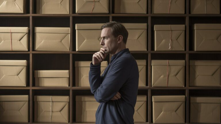 Galvojo žmogus, stovintis prieš tuščias dovanų dėžutes, apmąstančias kūrybines dovanas, dramatišką šoninį apšvietimą, kontempliatyvinę atmosferą, fotorealistinį portreto stilių su nuotaikingais šešėliais.