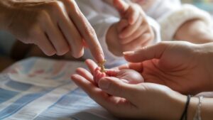 Realistiška nuotrauka: švelnios suaugusiųjų rankos, siūlančios mažą, simbolinę tradicinę krikšto dovaną mažyčiai kūdikio rankoms, šiltai šviesai, švelniai.