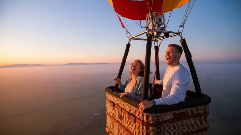 Pora džiaugsmingai juokiasi karšto oro balionų krepšyje, sklindančioje per kvapą gniaužiantį miglotą saulėtekio kraštovaizdį, plačiai kadrą, fotorealistinį.