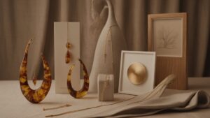 Realistiškas studijinis išskirtinių lietuvių prabangių dovanas: unikalūs gintaro papuošalai, dailios lininės tekstilės ir šiuolaikinio meno kūriniai, elegantiškai išdėstyti su minkštu, šiltu apšvietimu, pabrėžiančiu meistriškumu.