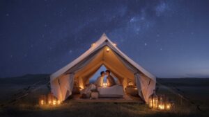 Kvapą gniaužiantis, realus platus poros kadras, pasidalinęs romantišku akimirka prabangioje, žvakių apšviestoje palapinėje po žvaigždės užpildytu dangumi, apsuptu subtiliai žvilgančių, eterinių žibintų, rodančių paslėptas galimybes ir vertę. Fotorealistinis.