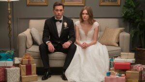 Realistiška nuotrauka: Šiuolaikiški jaunavedžiai, mandagus, tačiau subtilus nusivylimo žvilgsnis, esant didelei krūvai generinių, nereikalingų vestuvių dovanų.