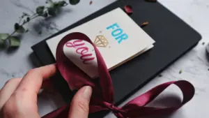 Dovanų kortelė su kaspinu ir užrašymu „For you“ ant stalo